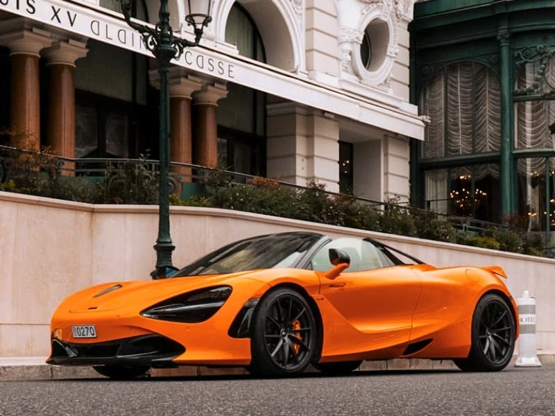 Oranžové luxusné auto v Monaku pred hotelom.