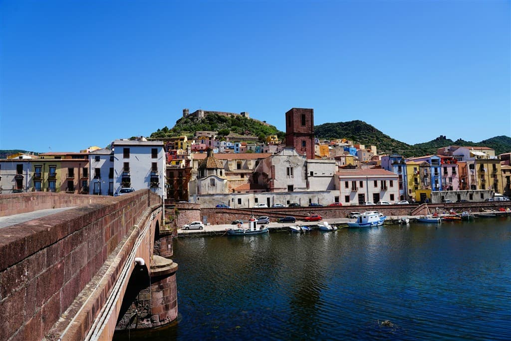 Kamenný most, prístav, domy v Bosse na Sardínii.