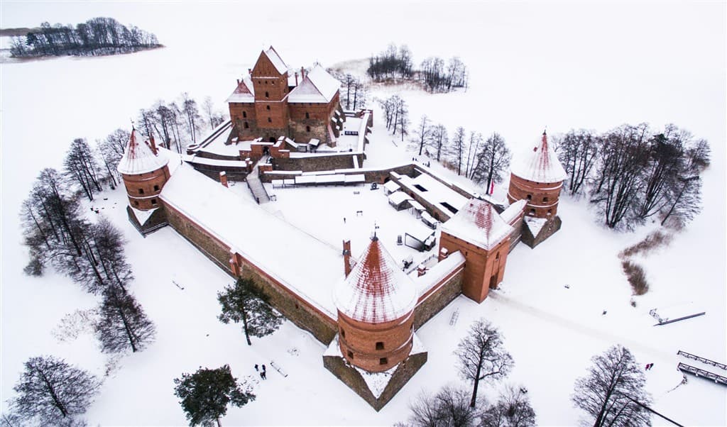 Zasnežený hrad Trakai v Litve a okolité stromy.