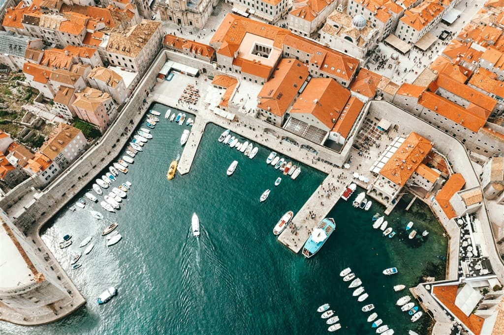 Prístav s loďami a červené strechy na domoch v Dubrovníku.