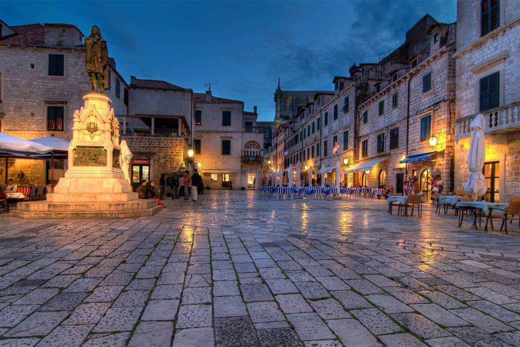 Dláždená ulica a staré domy v Dubrovníku po západe slnka.
