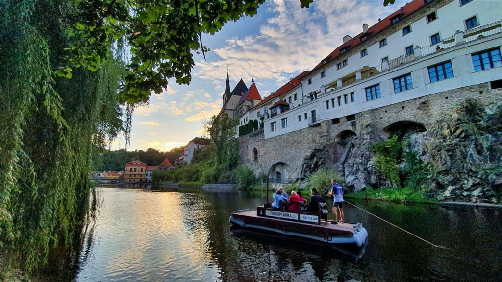 Turisti na lodi na rieke a hradný areál v Českom Krumlove.