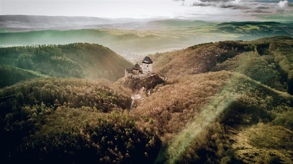 Kopce, stromy a hrad Karlštejn.