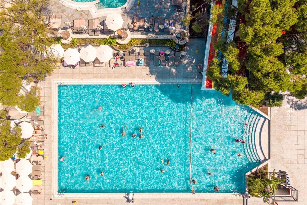 veľký vonkajší bazén v zelenom hotelovom areáli