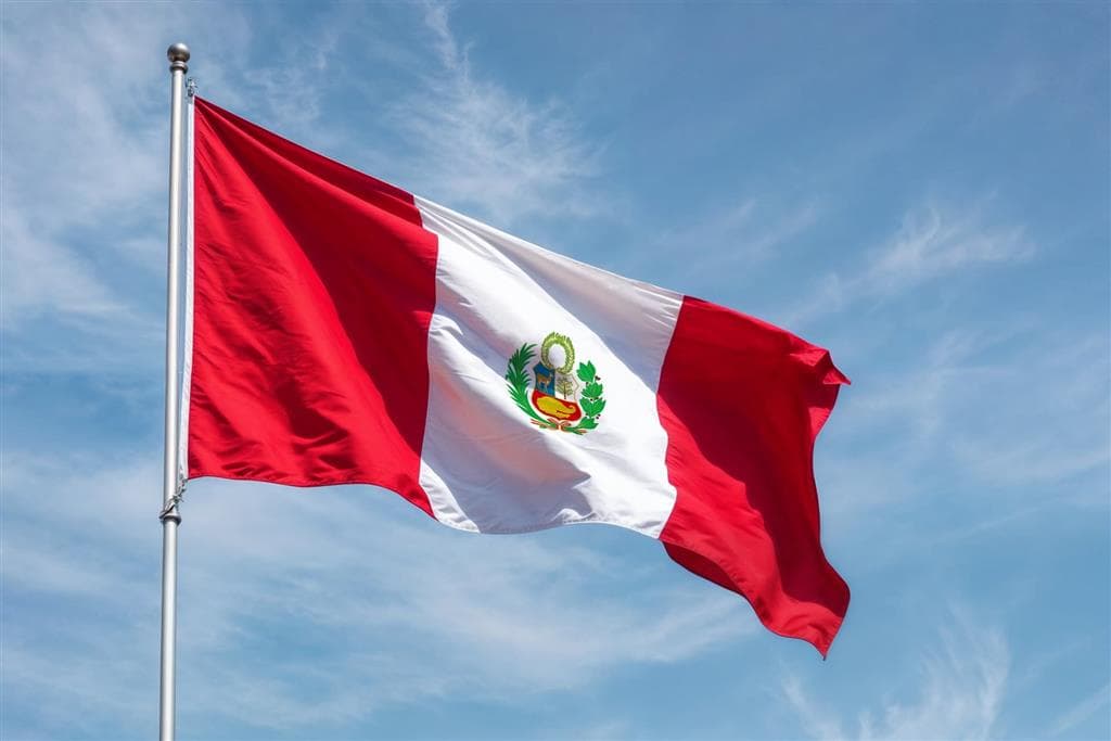Štátna vlajka Peru vejúca na stožiari pod modrou oblohou