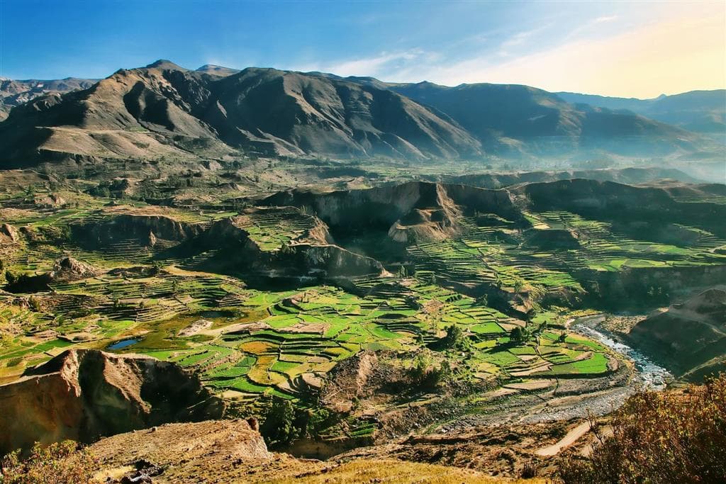 Pohľad na hlboký kaňon Colca v Peru s terasovitými poliami a majestátnymi andskými scenériami