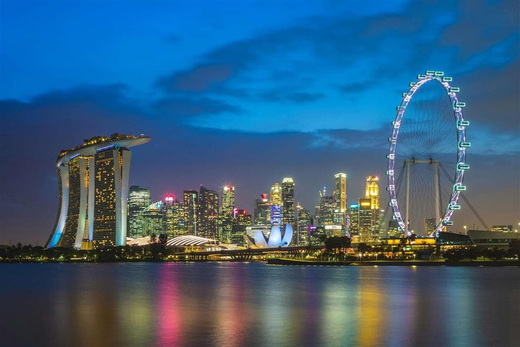 Osvetlená panoráma Singaporu ukazuje tri dominanty Marina Bay – hotel Marina Bay Sands, vyhliadkové koleso Singapore Flyer a lotosovú stavbu ArtScience Museum