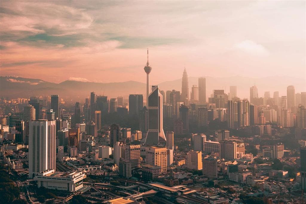Západ slnka nad Kuala Lumpur odhaľuje hustú mestskú štruktúru a výškové budovy, ktoré dokumentujú rýchlu urbanizáciu Malajzie